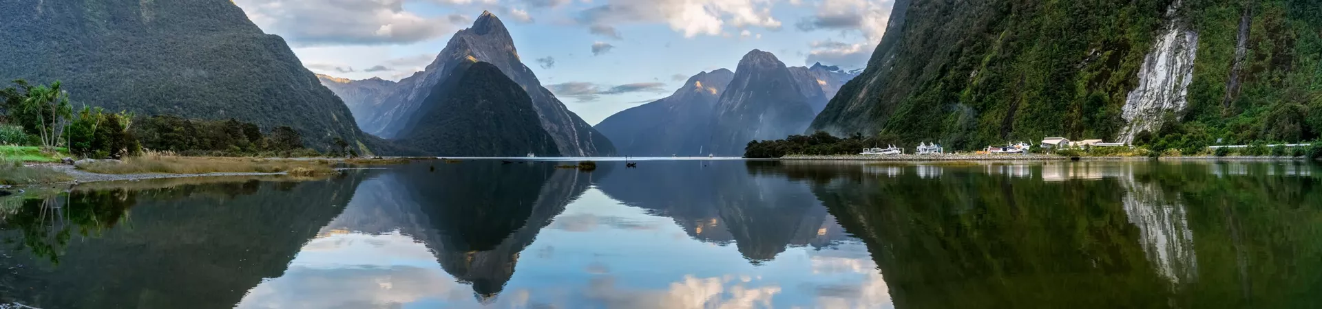 Scenic panorama of mountains reflecting on the shiny surface of Milford Sound, New Zealand
