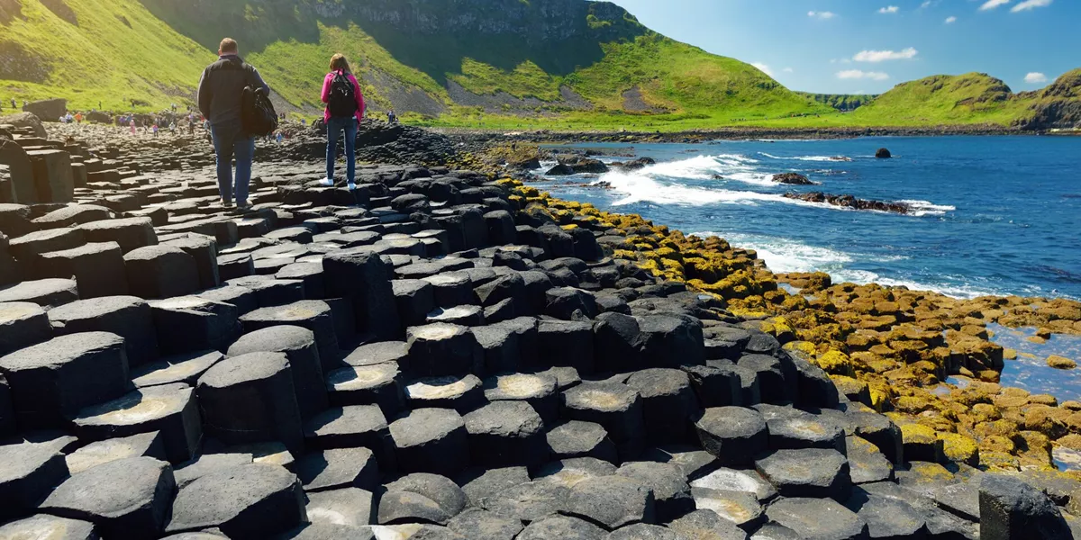 Large Two Tourists Walking At Giants Causeway, An Area Of Hexagonal Basalt Stones, County Antrim, Northern Ireland Famous Tourist Attraction, UNESCO World H 1174538488