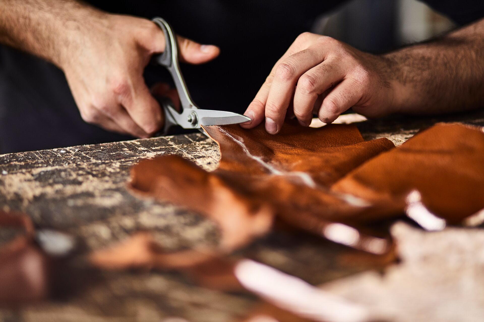 Close up view of a man cutting leather in a workshop