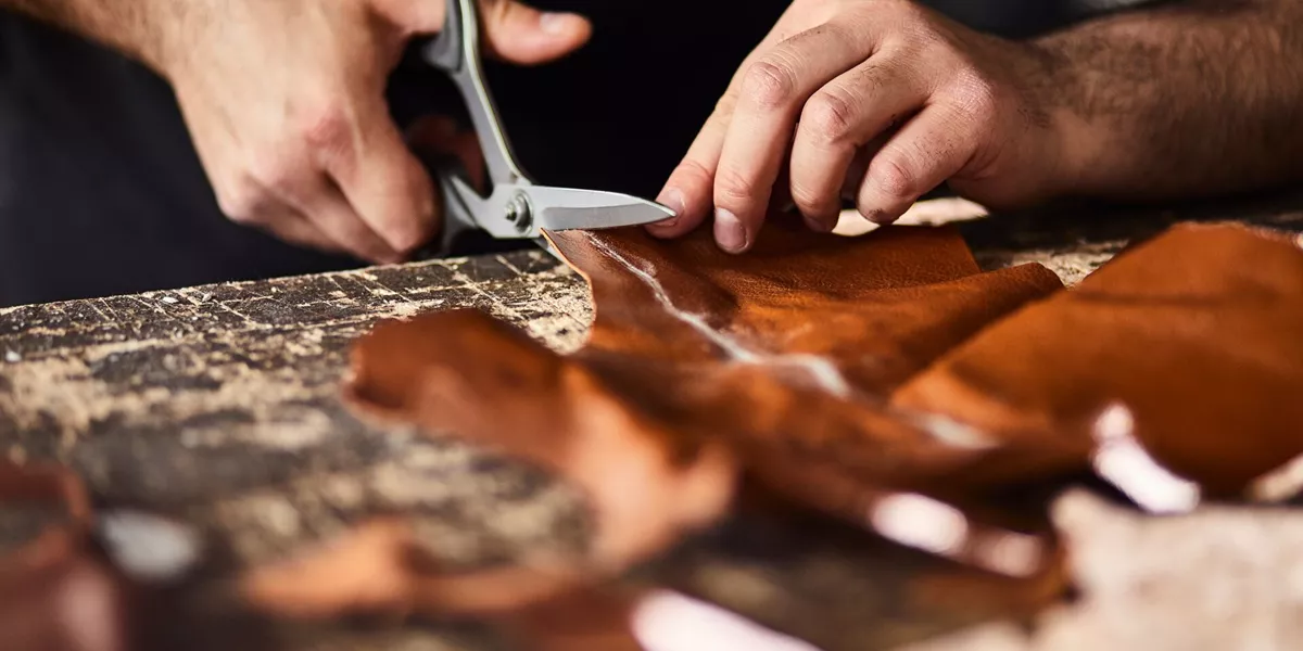 Close up view of a man cutting leather in a workshop