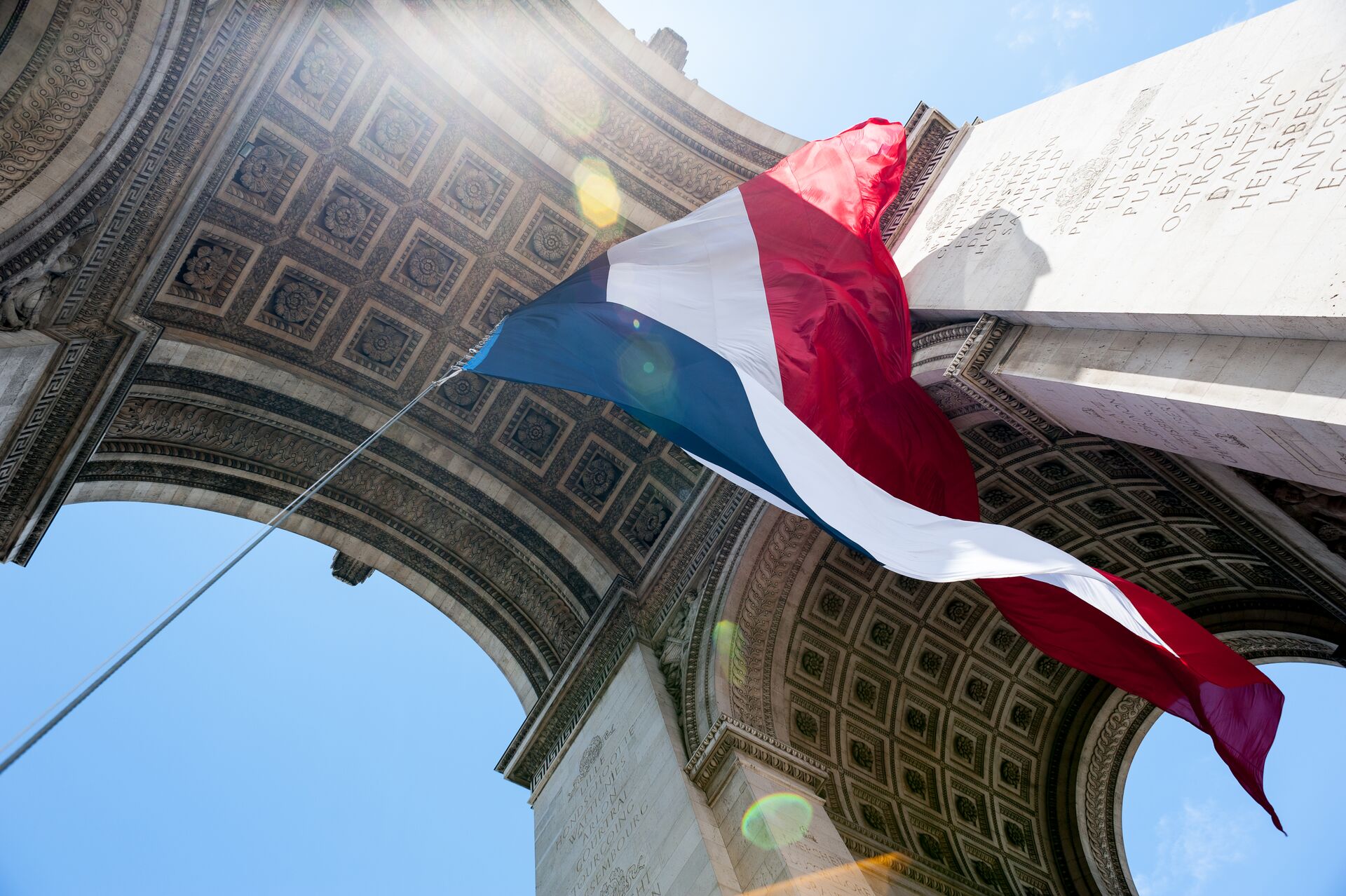 The tri-colour flying underneath the Arc de Triomphe in Paris, France on Bastille Day