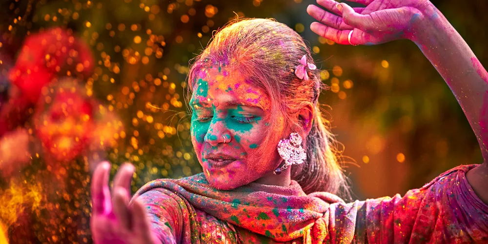 Woman With Colored Face Dancing During Holi festival in India