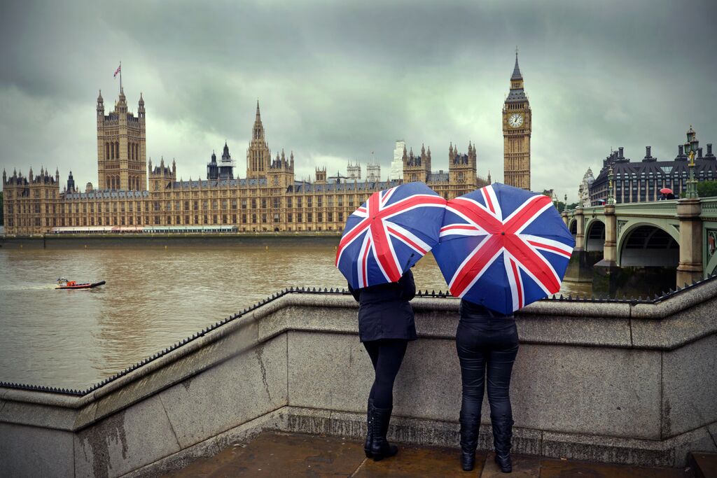 Two women with Union Jack umbrellas overlooking London