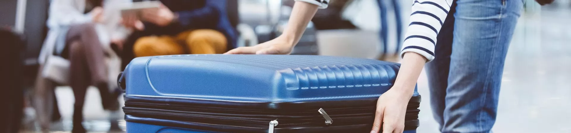 Woman in a stripy top picking up her suitcase at the airport