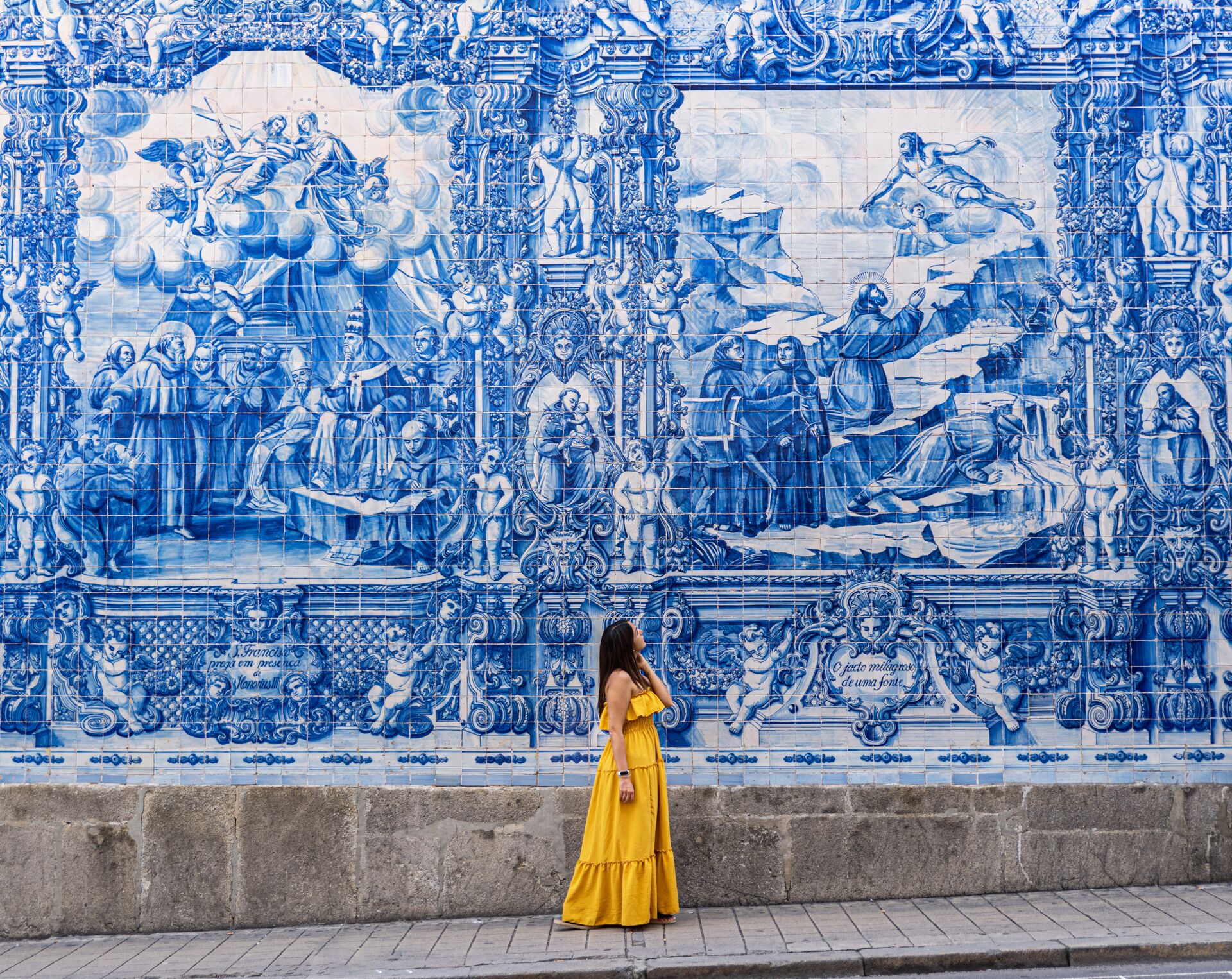 Women dressed in yellow admiring the iconic blue and white tiles in Porto, Portugal