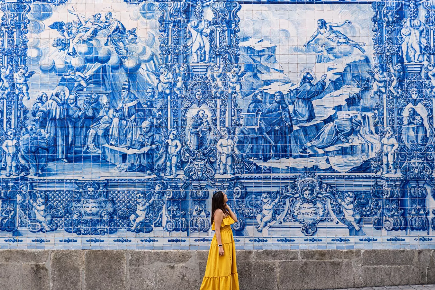 Women dressed in yellow admiring the iconic blue and white tiles in Porto, Portugal