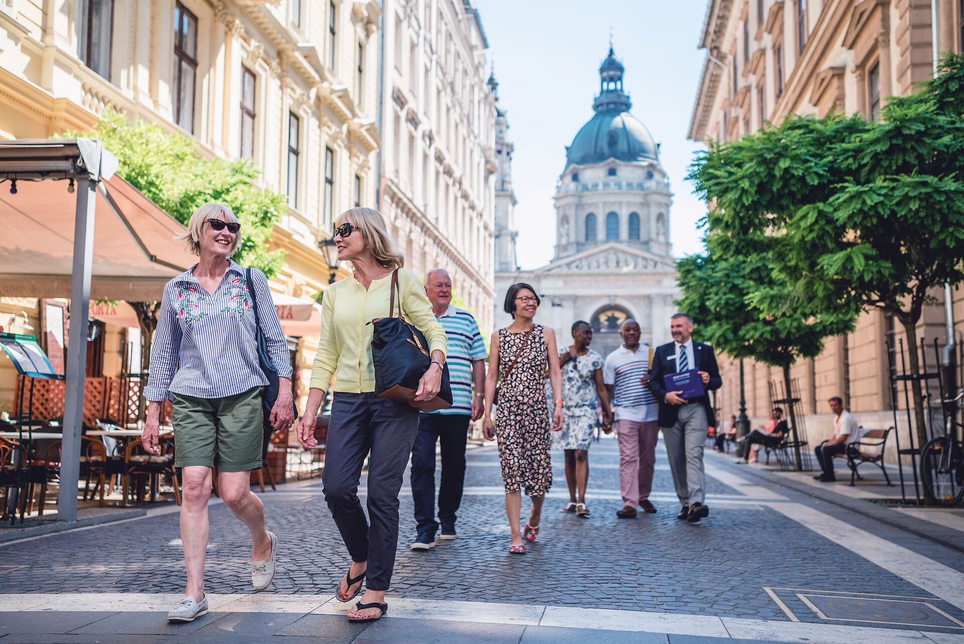 A group of casually dressed tourists explore a pretty street in a European city
