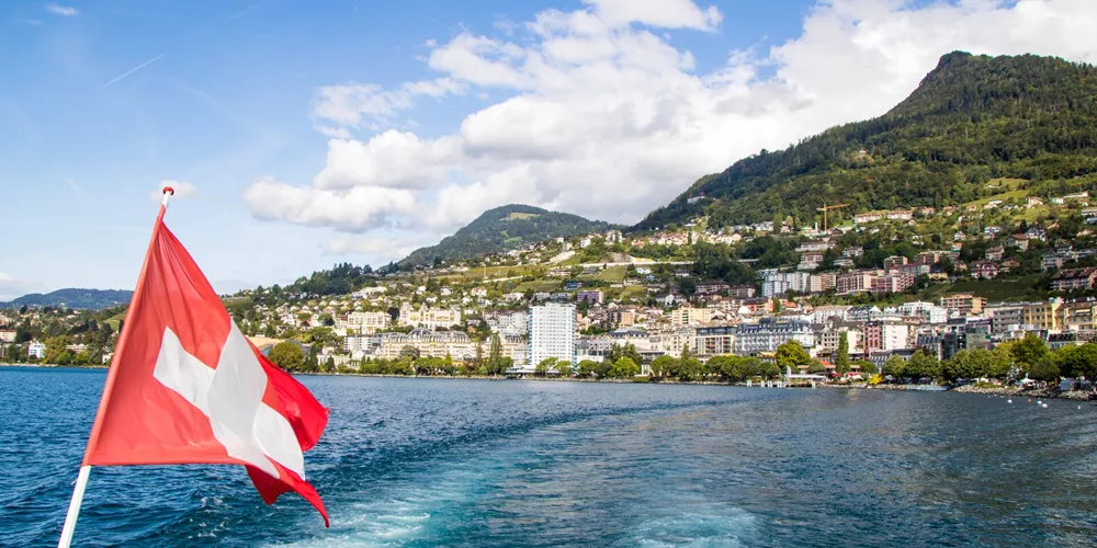 Swiss flag in the foreground with Geneva in a the background