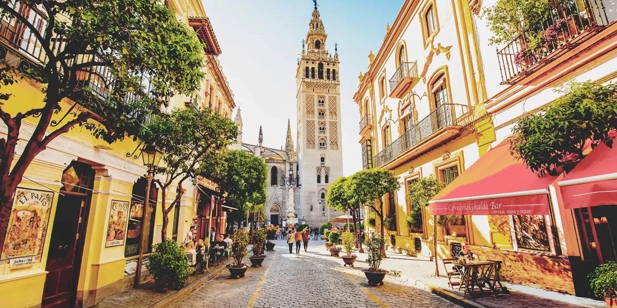 Sunny Seville street and scenic view of Giralda tower, Seville, Spain