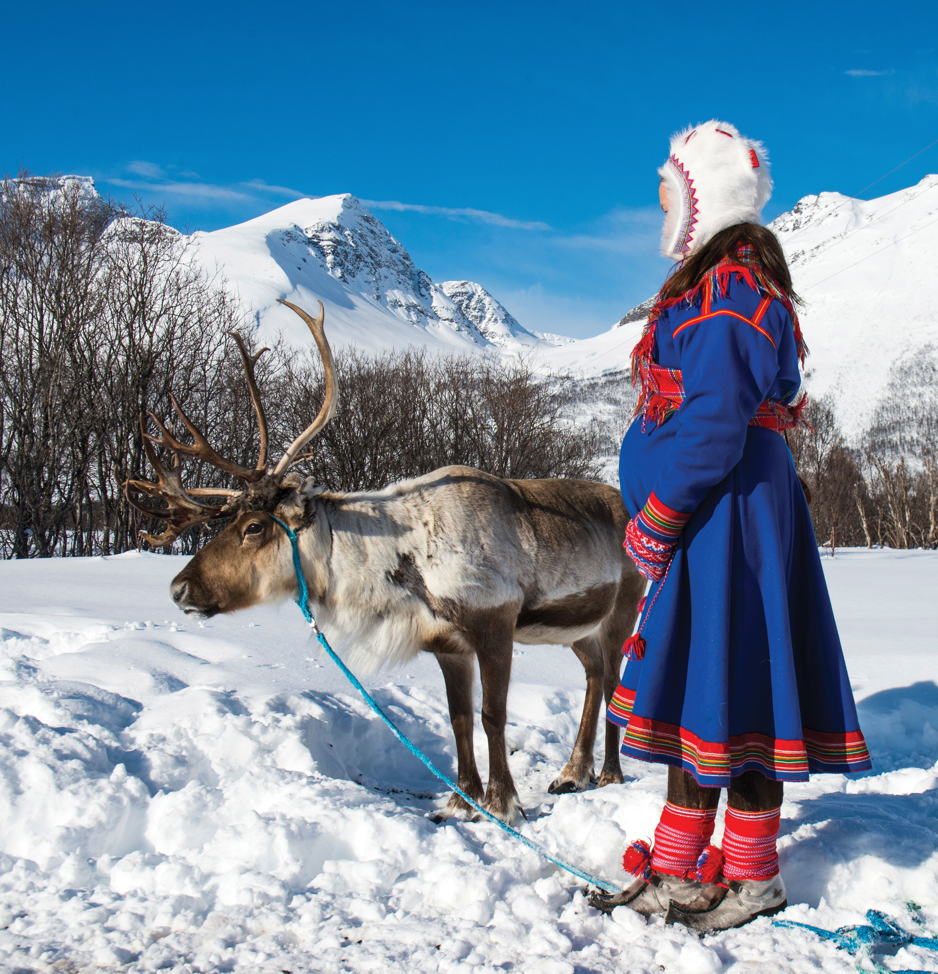 A woman and a reindeer surrounded by winter landscape