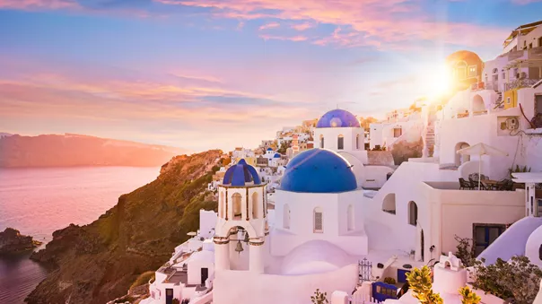Sun setting over the blue dome churches of Oia in Santorini, Greece
