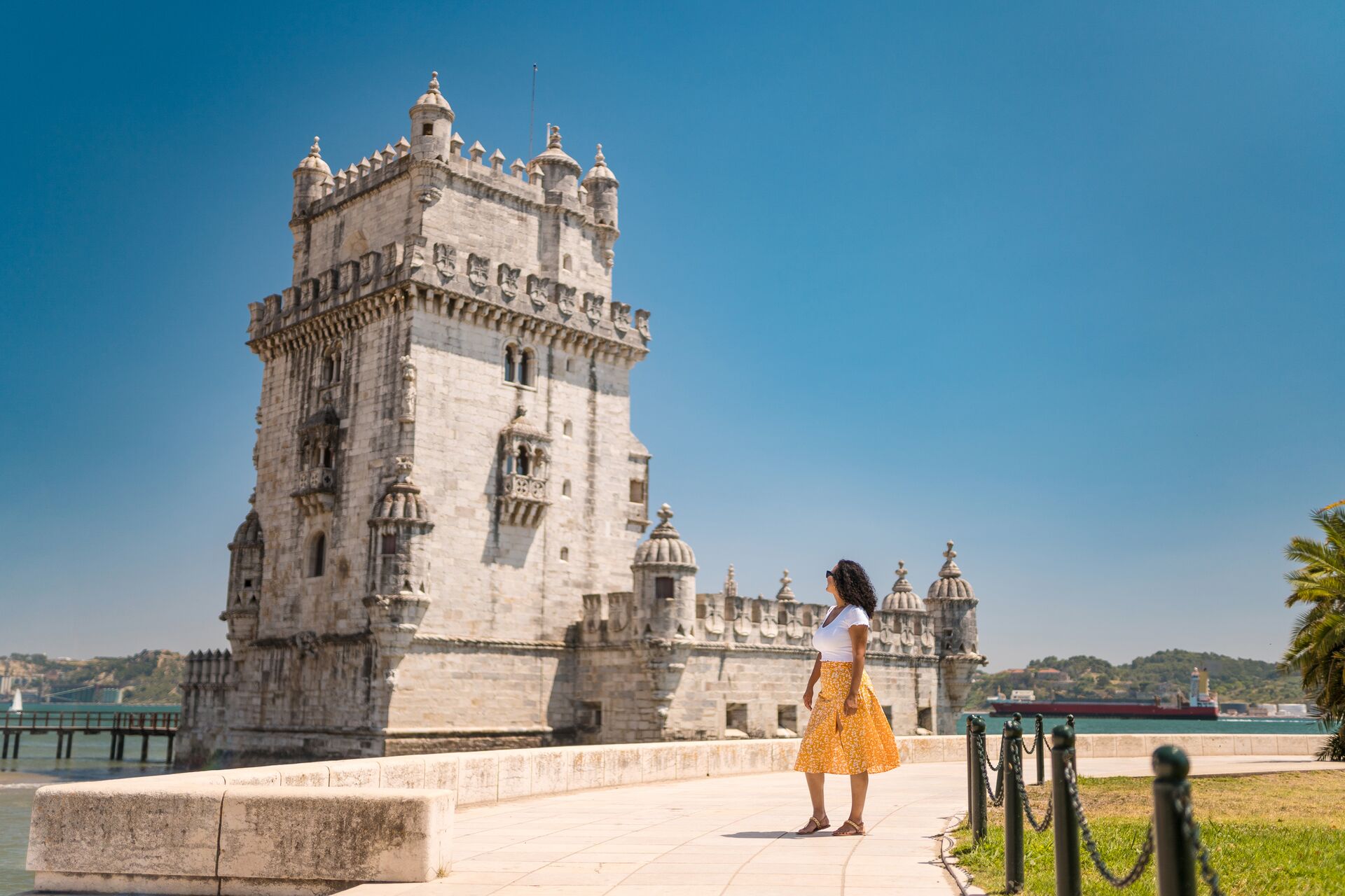 Female tourist staring back at the Tower of Belem in Lisbon, Portugal