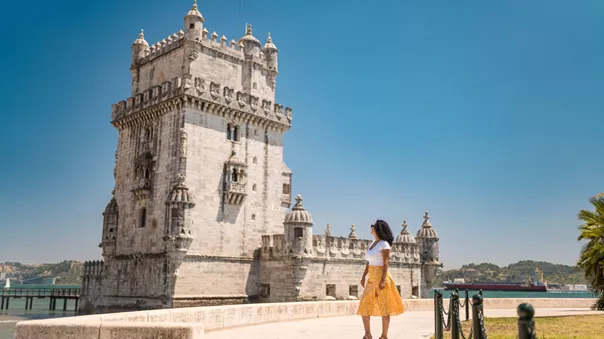 Female tourist staring back at the Tower of Belem in Lisbon, Portugal