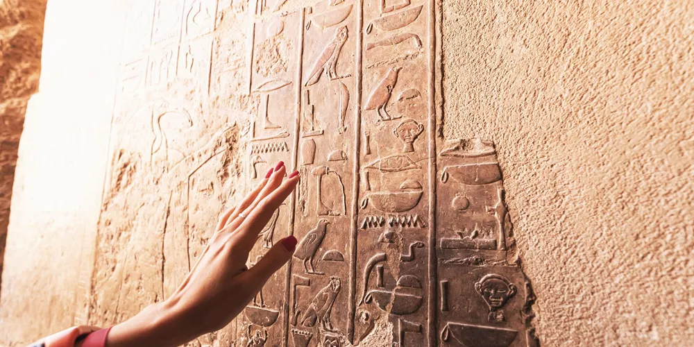 An Egyptologist or archaeologist reads and translates Egyptian hieroglyphs carved in stone