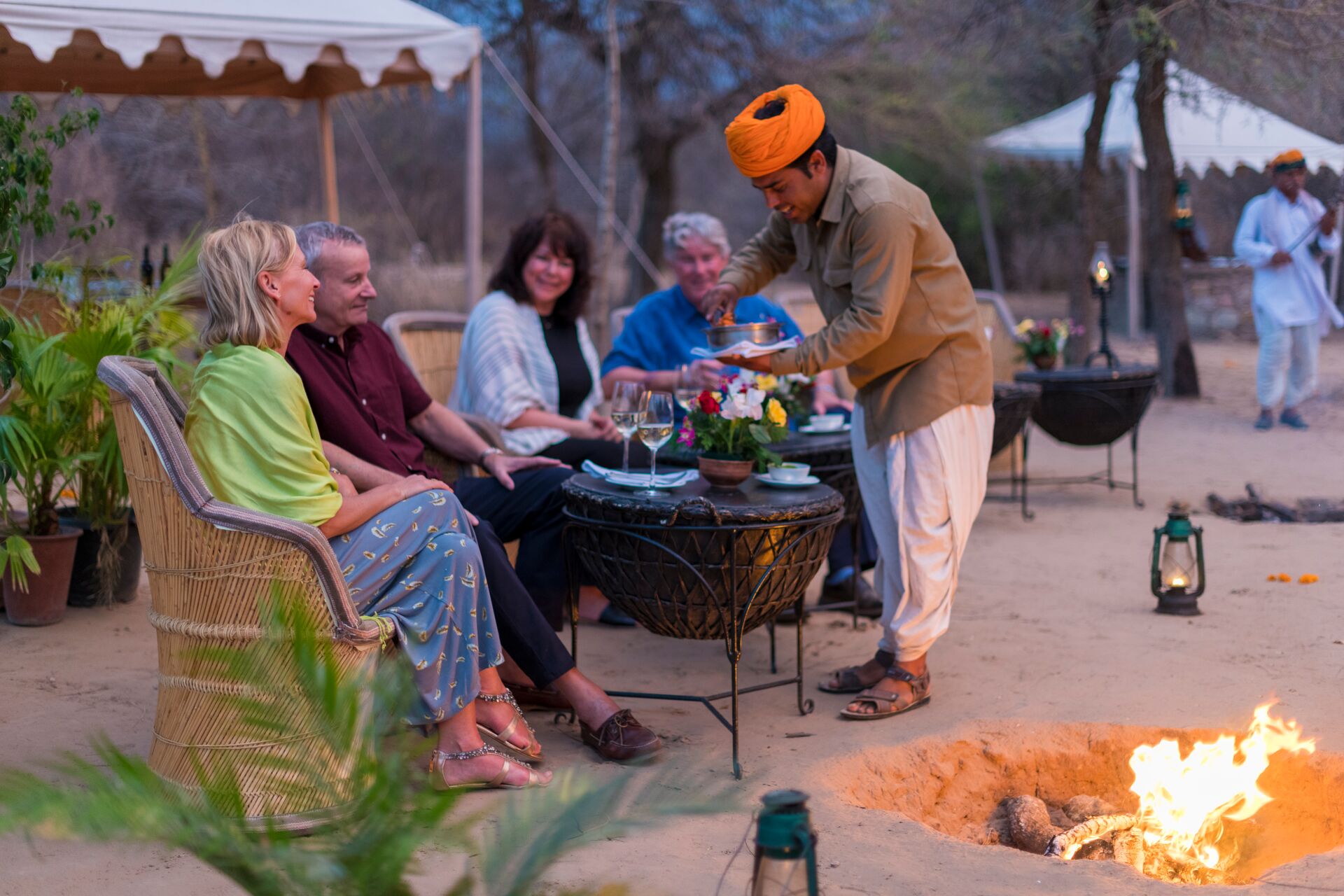 Guests are served wine at tables outside in the Aravalli Mountains, India