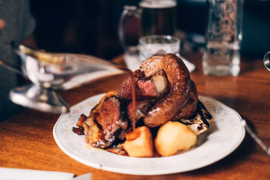 Pouring Gravy Over Roasted Meat in an English Pub