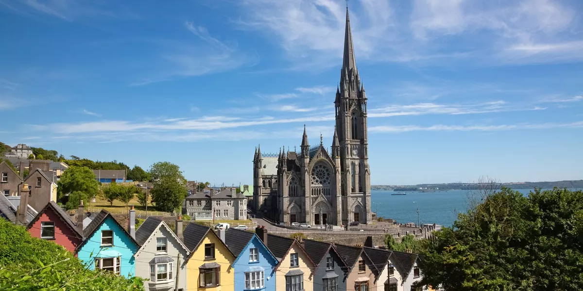 A row of colourful houses with Saint Colmans Cathedral in the background in Cobh, County Cork, Ireland
