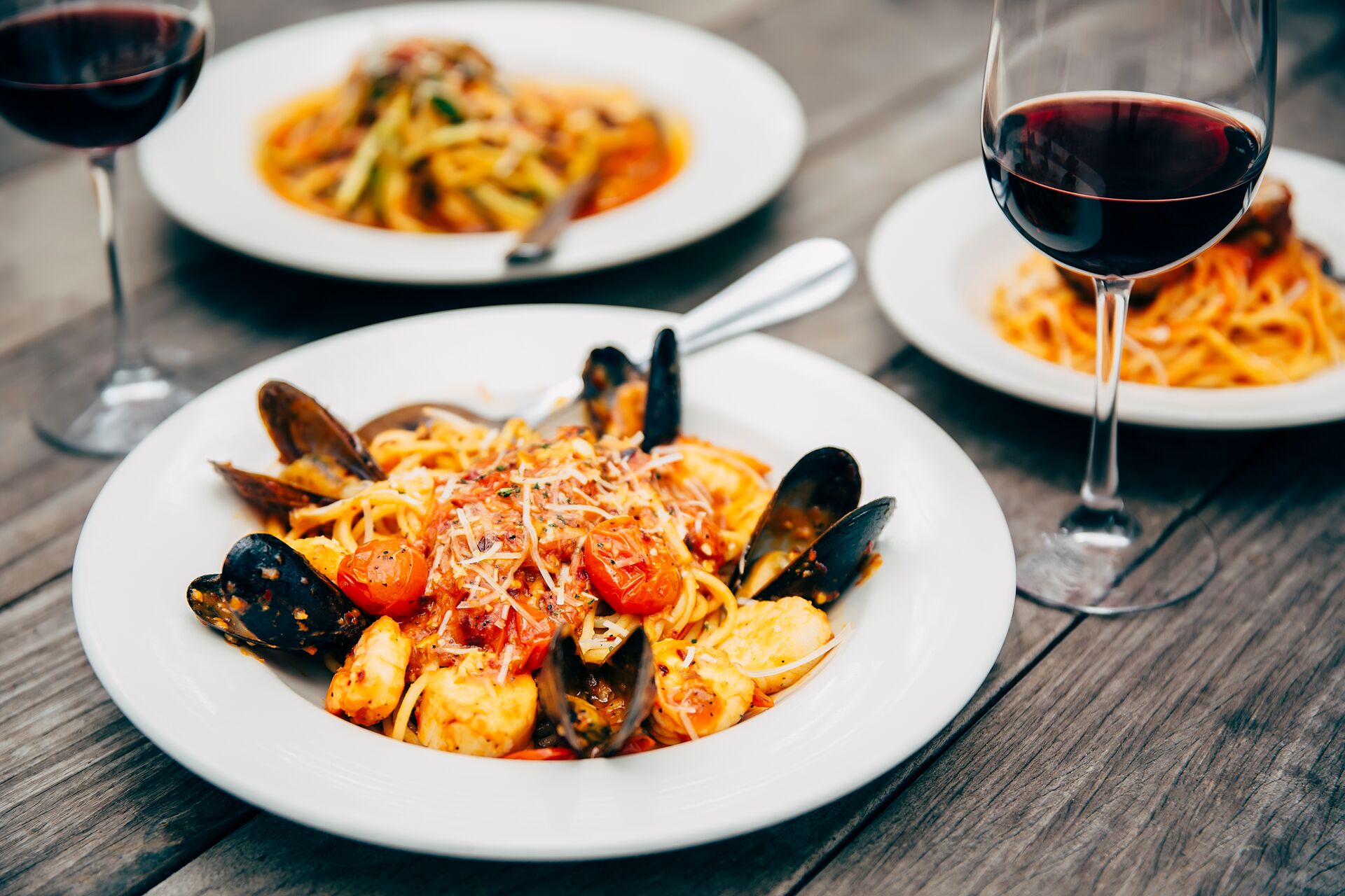 Plates Of Seafood And Pasta With Wine Glasses in Italy