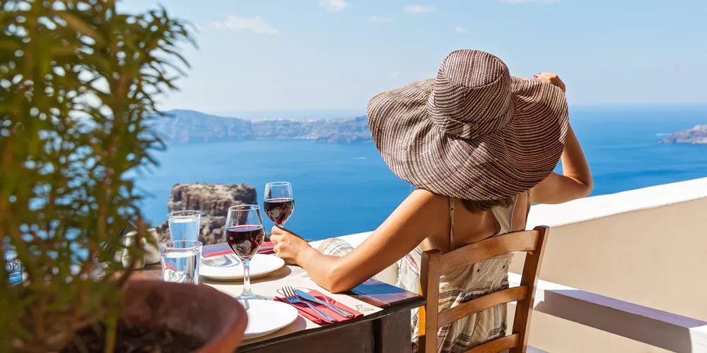 Woman drinking wine while looking out at the Mediterranean Sea