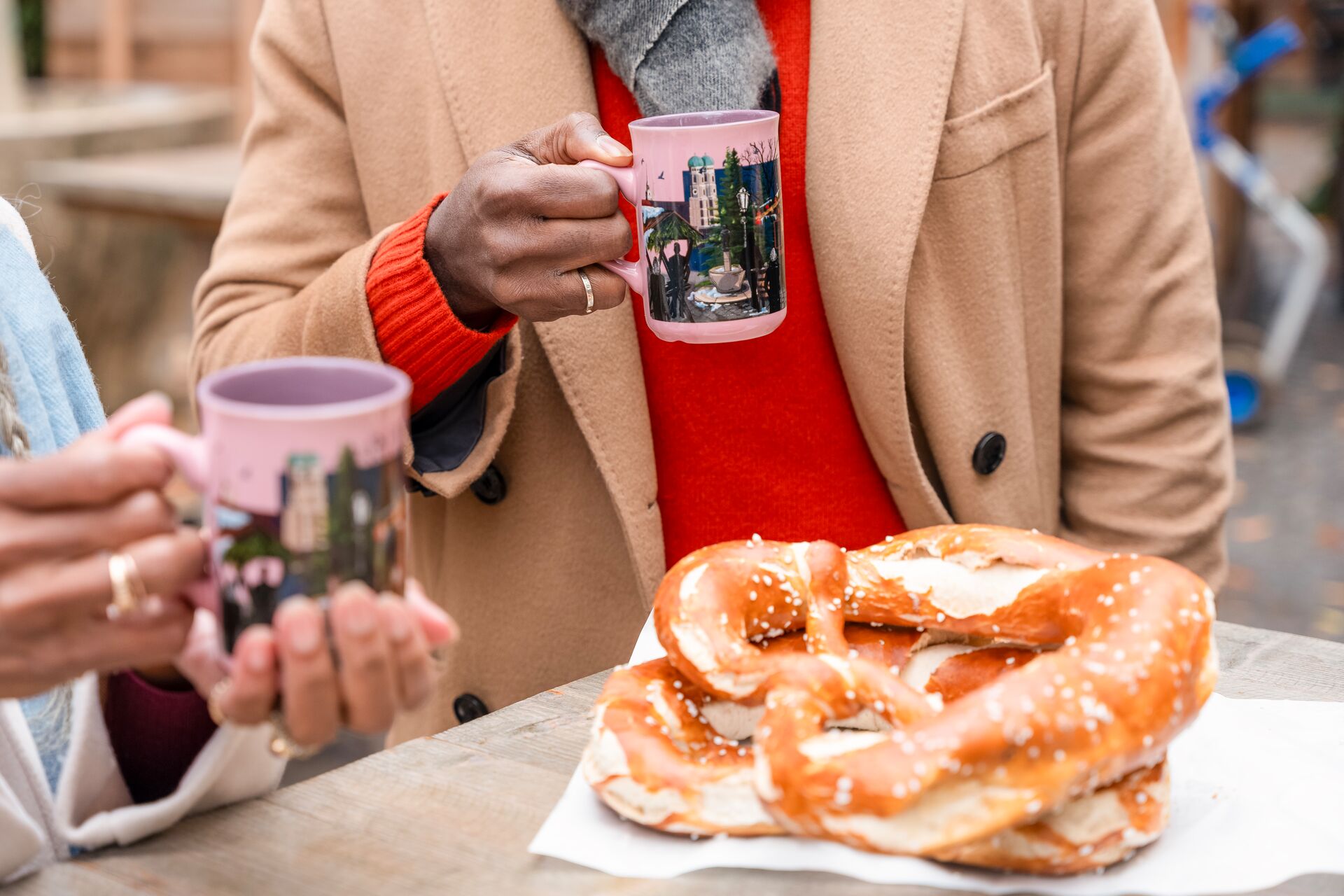 Guests holding Gluhwien and eating pretzels at a German Chrismtas Market
