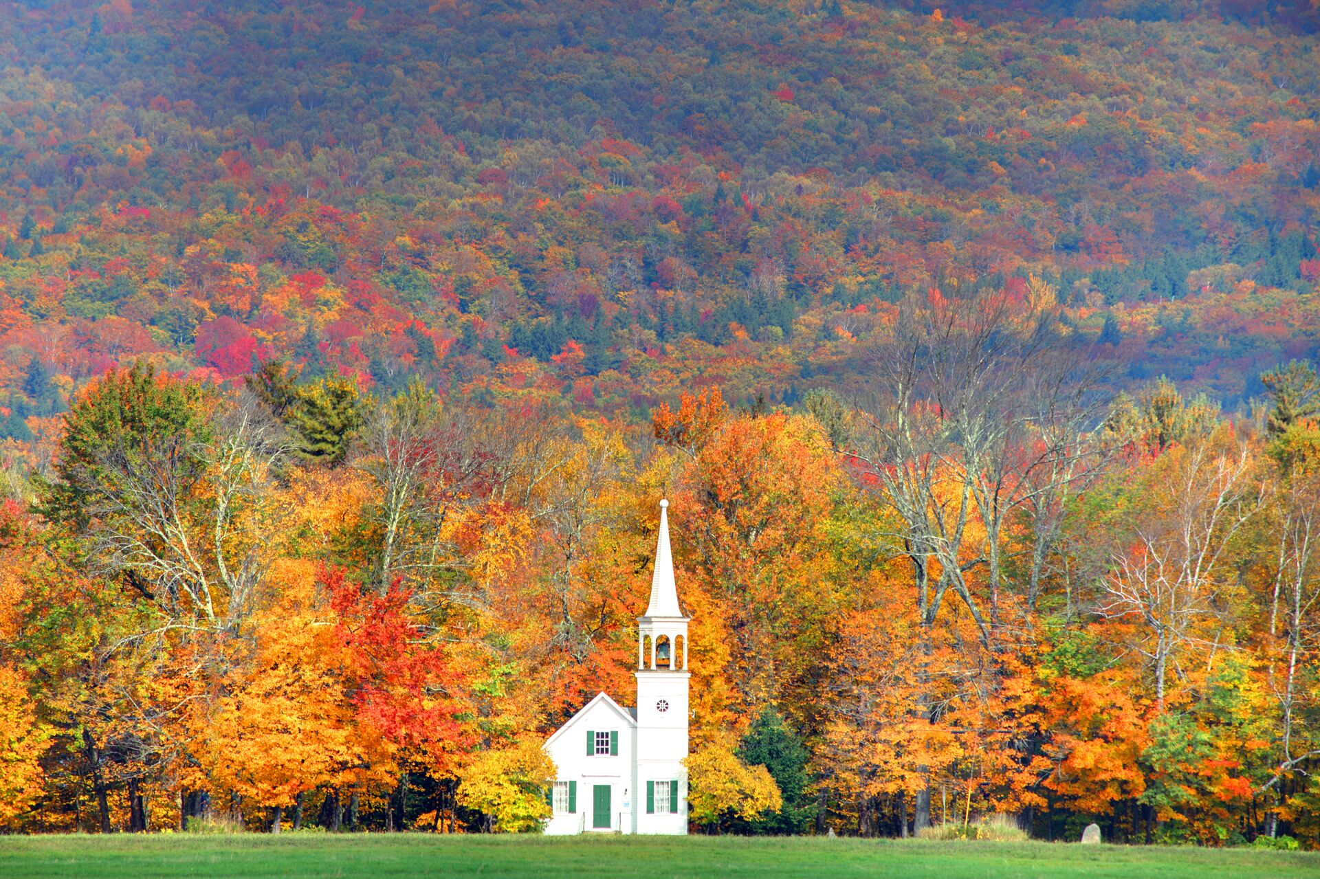 White church in front of autumnal trees during fall in New England