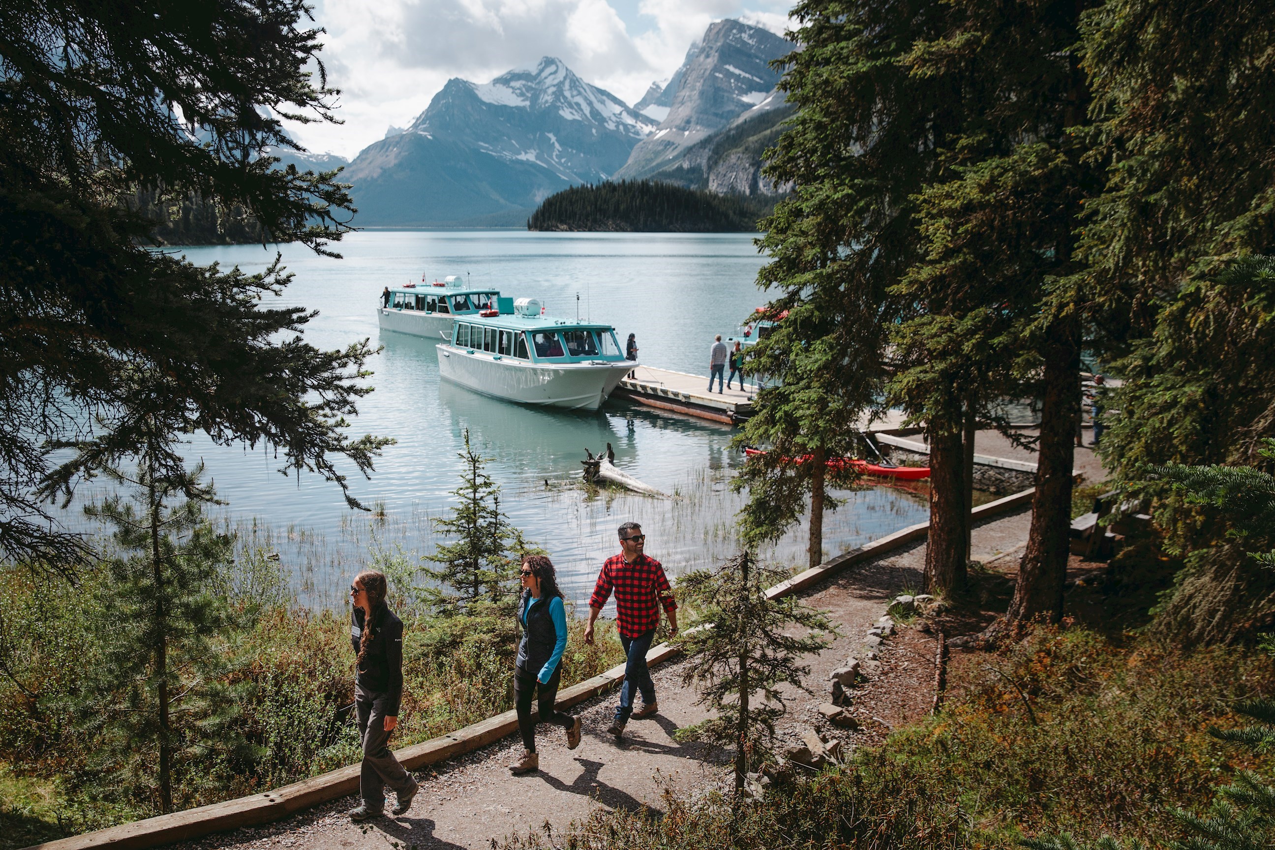 Group of people walking next to Maligne Lake on a sunny day in Jasper, Canada