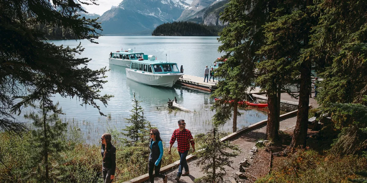 Group of people walking next to Maligne Lake on a sunny day in Jasper, Canada