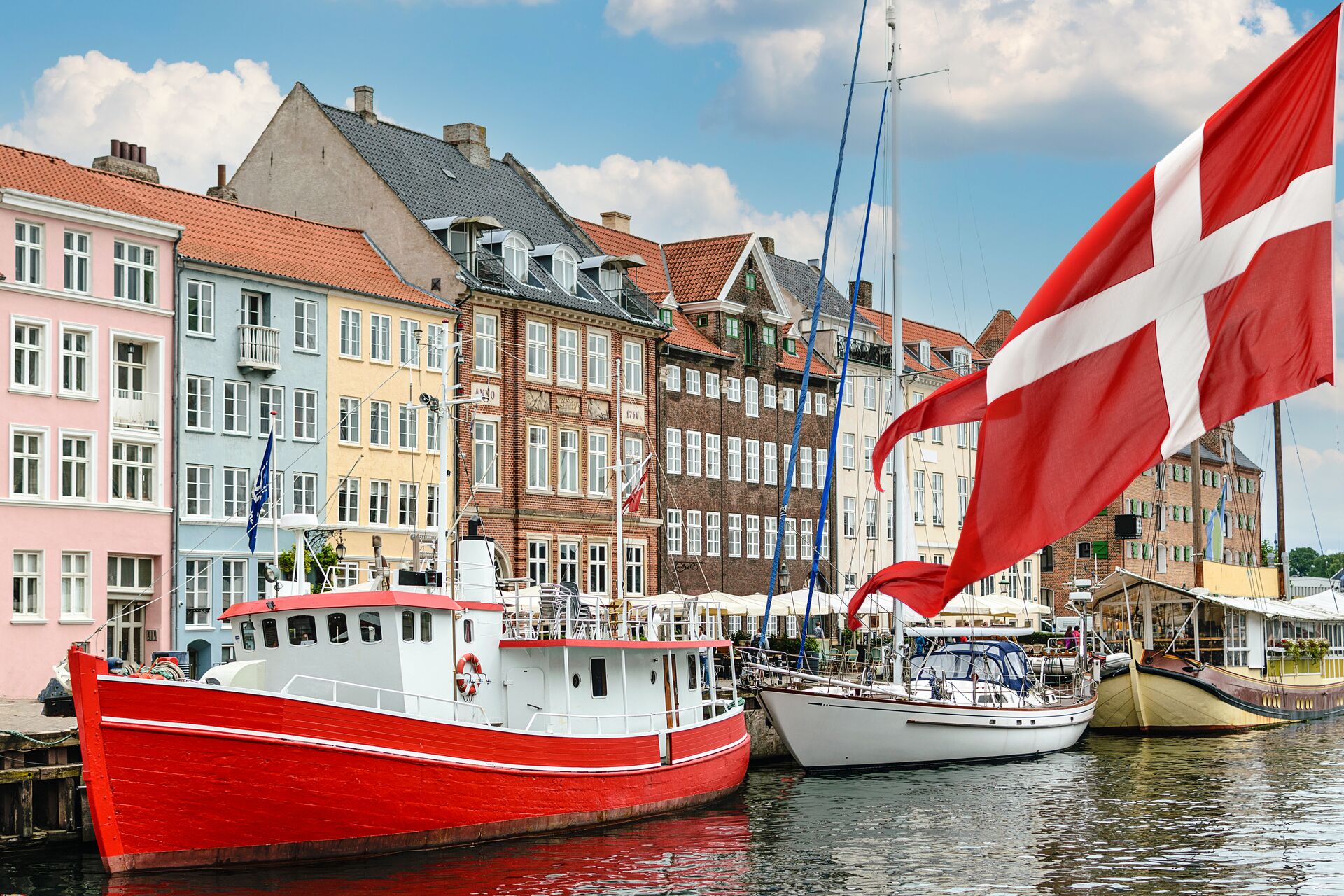 Boats in the harbour of Copenhagen with the Danish flag in the foreground