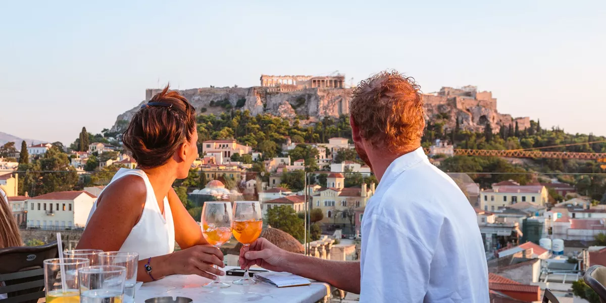 Couple drinking in front of the Acropolis at sunset in Athens, Greece