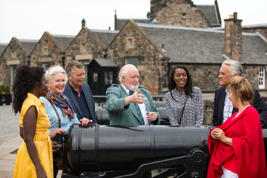 Local expert talking to a small group of tourists next to a canon at Edinburgh Castle in Edinburgh, Scotland