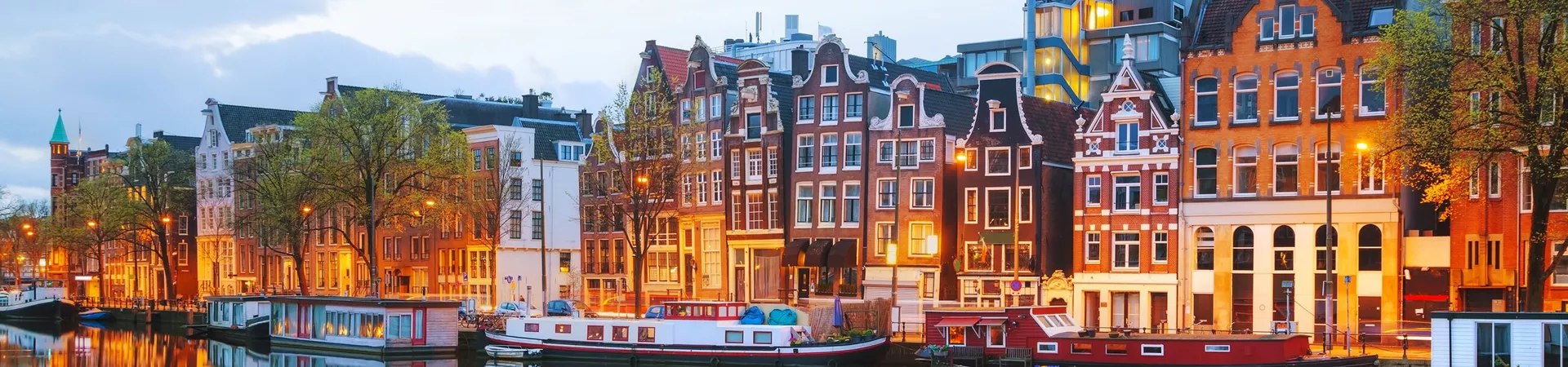Traditional houses and canal lit up at night in Amsterdam, The Netherlands
