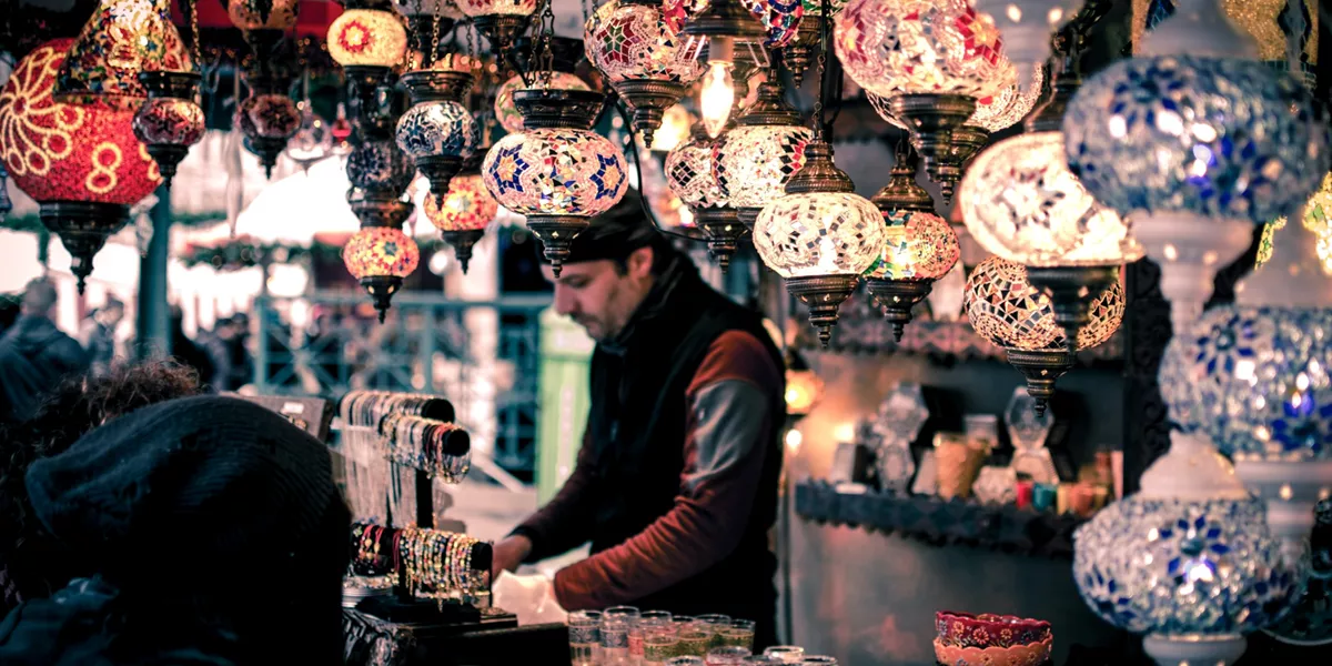 A man on a market with Moroccan lamps. 