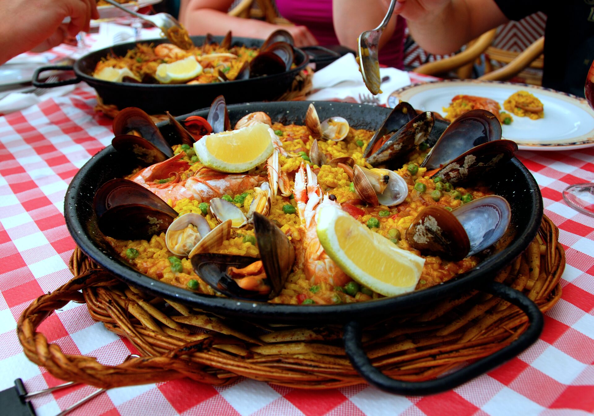 A black pan pf Paella on a checkered tablecloth