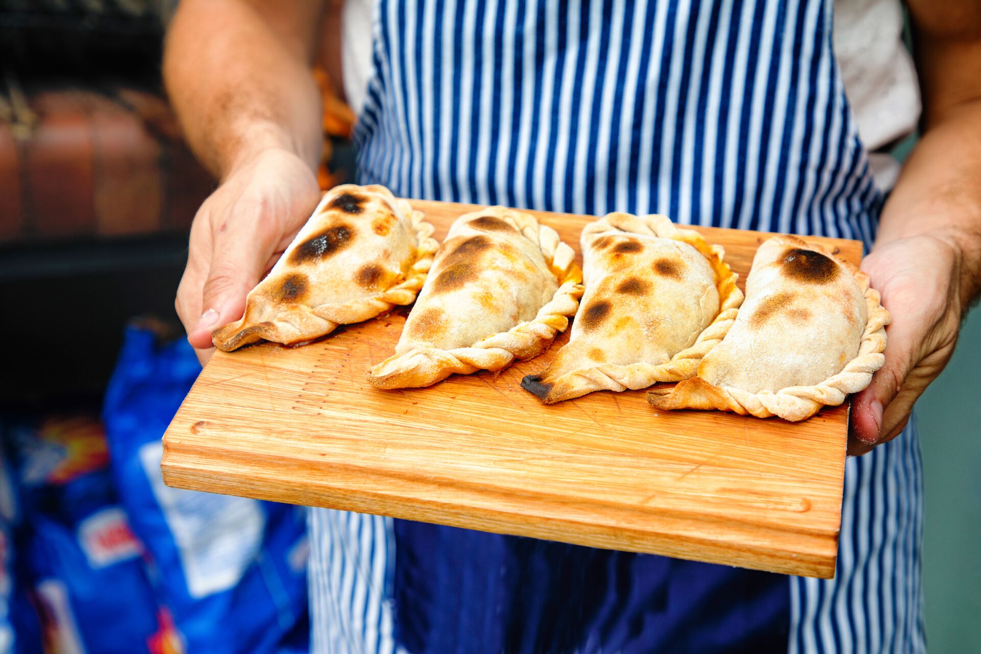 Large Close Up On Perfectly Baked Empanadas Tucumanas On A Cutting Board Held By Baker 1188696841