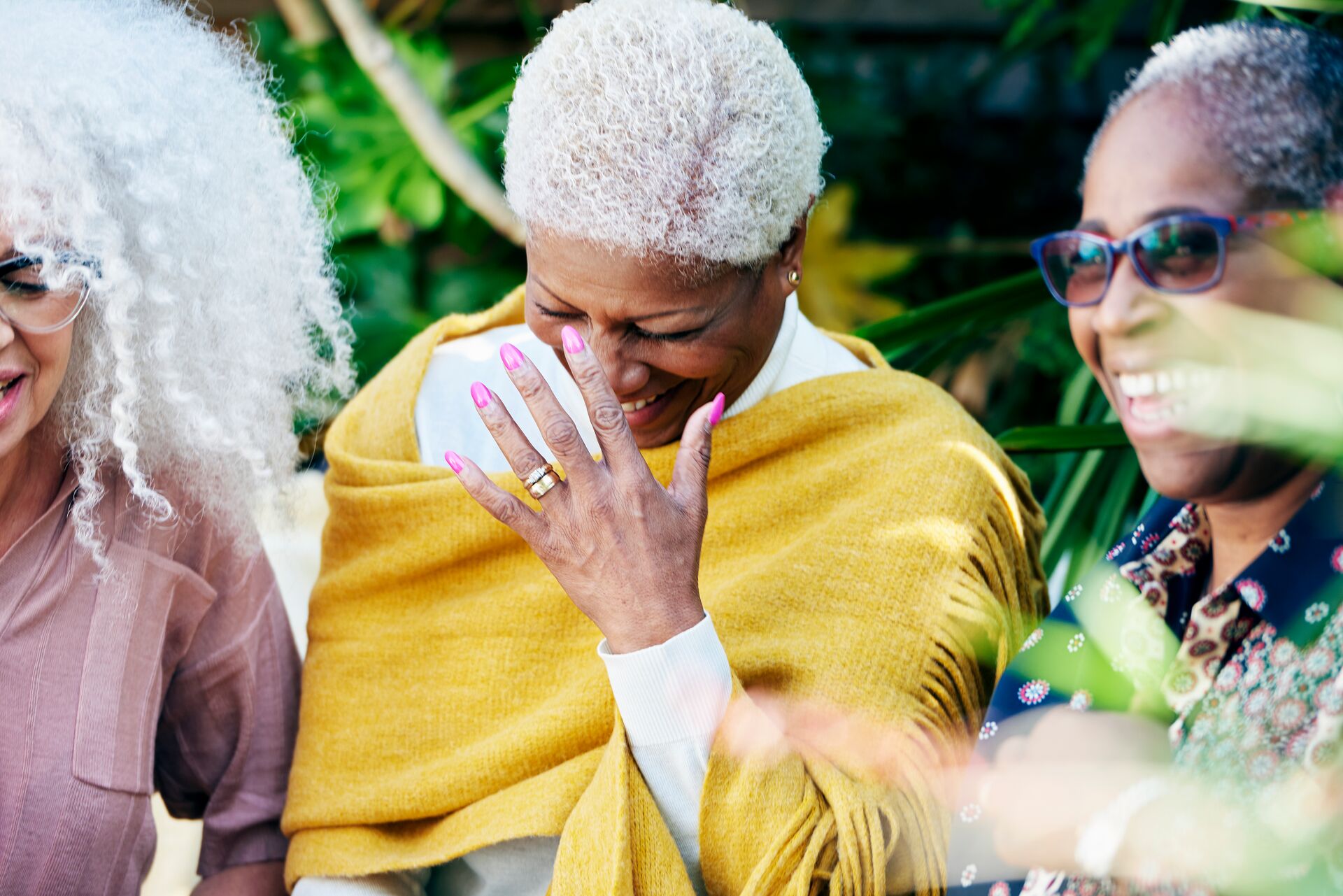 Three senior women in a garden laughing