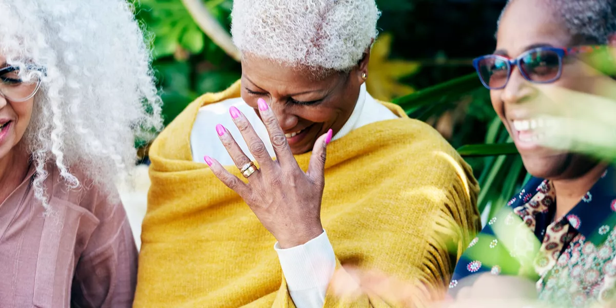 Three senior women in a garden laughing