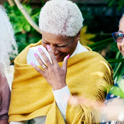 Three senior women in a garden laughing