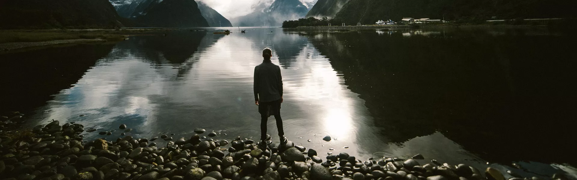 A man standing in front of the mountains and a lake