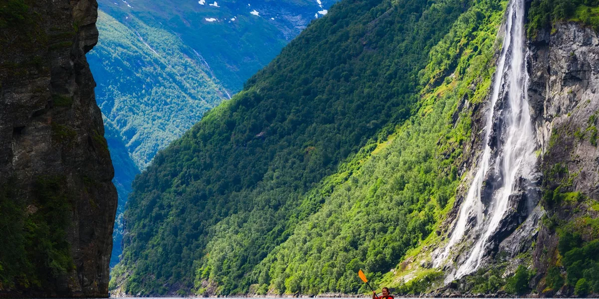 Person kayaking up a fjord in Norway, Scandinavia on a sunny day