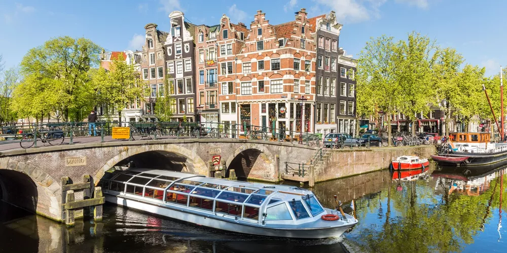 Boat passing under a bridge while sailing down a canal in Amsterdam, Holland, Netherlands