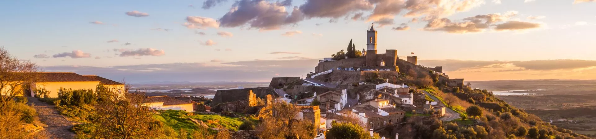 A hilltop town in Portugal surrounded by lush countryside. Sunset so the light is golden on the buildings.