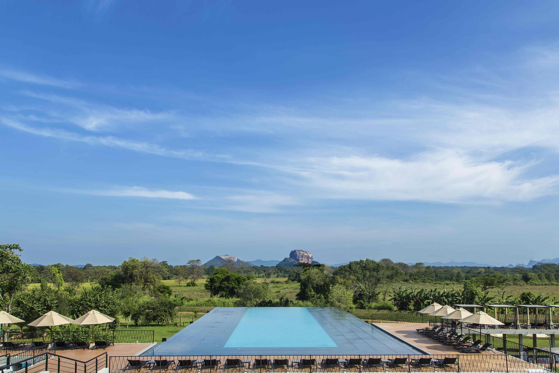 The swimming pool of the Aliya Resort and Spa in Sri Lanka with mountains in the distance