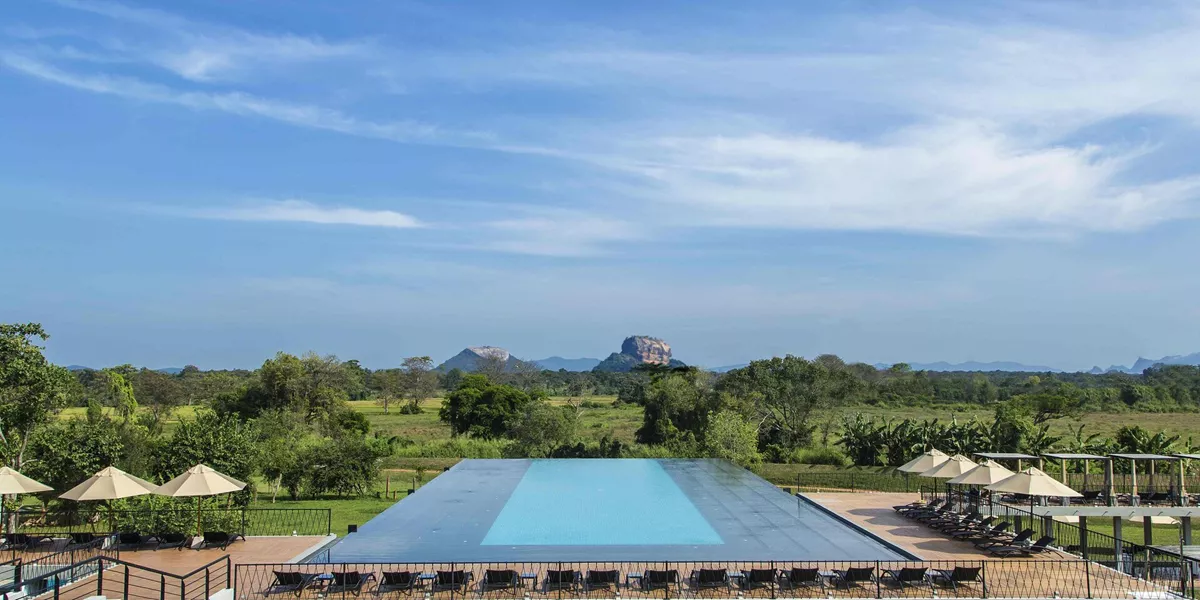 The swimming pool of the Aliya Resort and Spa in Sri Lanka with mountains in the distance