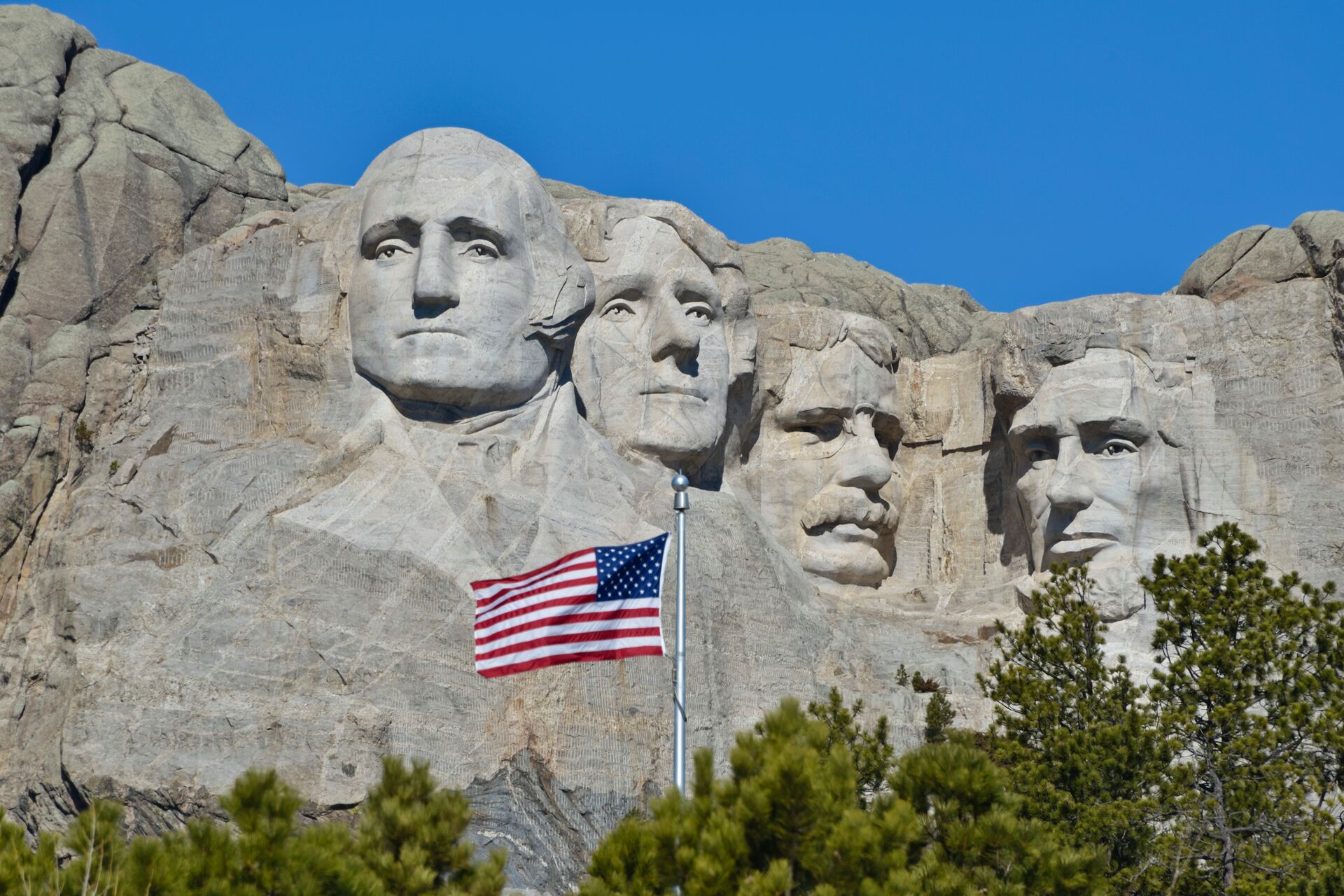 Mount Rushmore National Monument in the Black Hill region of South Dakota, USA with the US flag in the foreground
