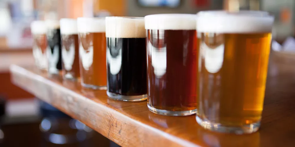 Row of different beers on a wooden bar