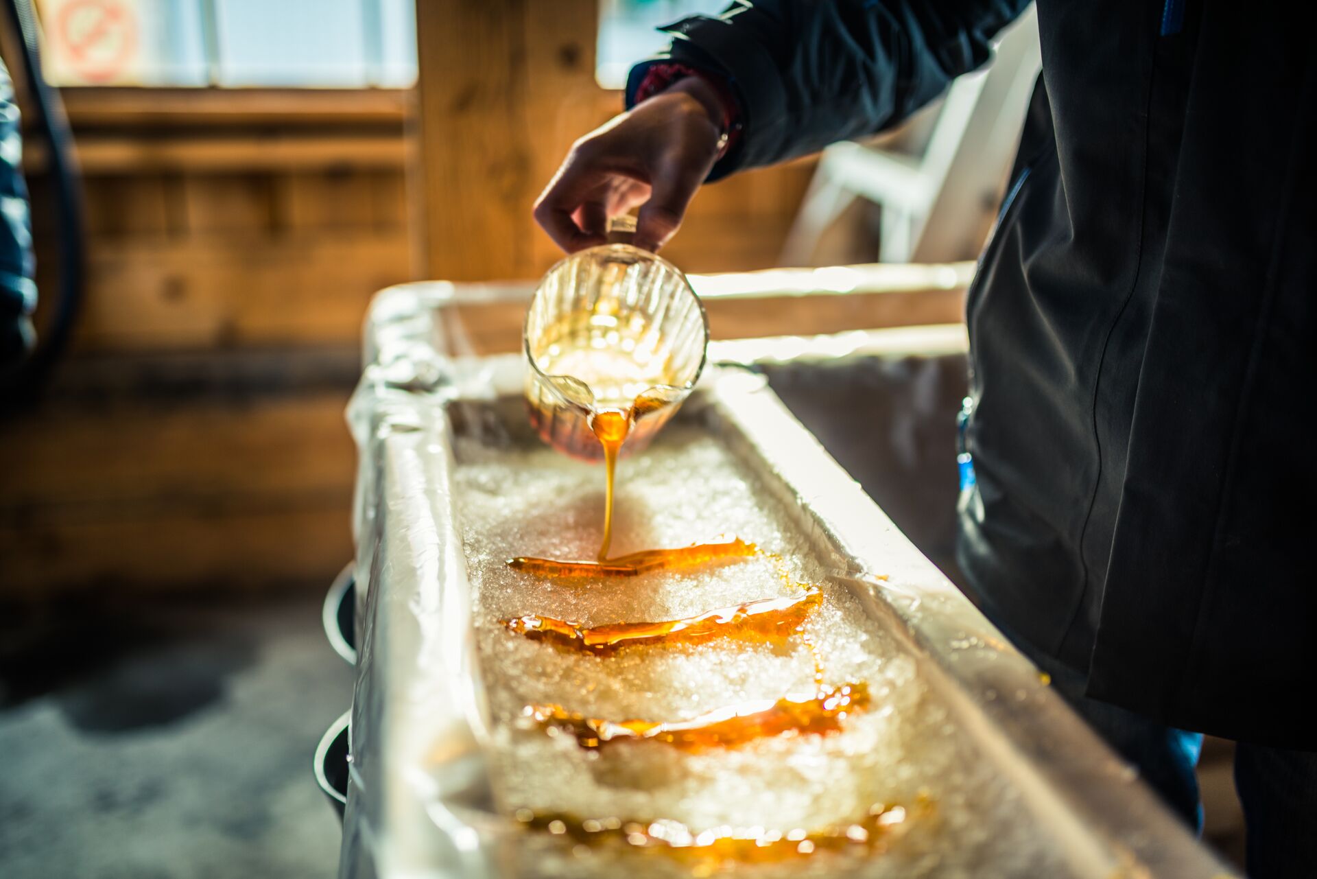 Person pouring maple syrup onto snow in Vermont, USA