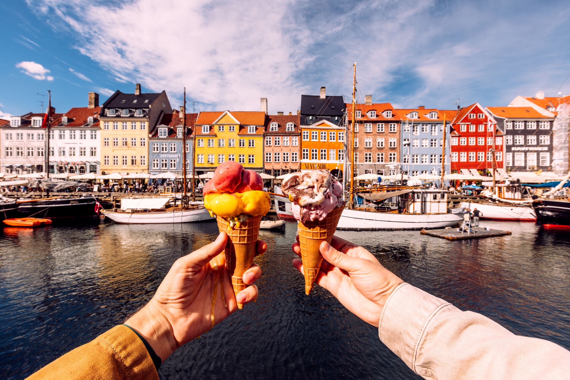 Two persons holding colourful ice cream by Nyhavn harbour in Copenhagen, Denmark