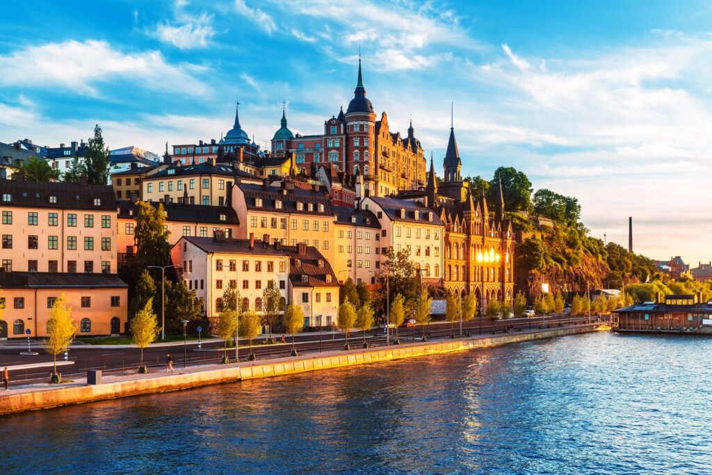 Buildings in Stockholm in Sweden gleam in the sunset next to dark blue river.