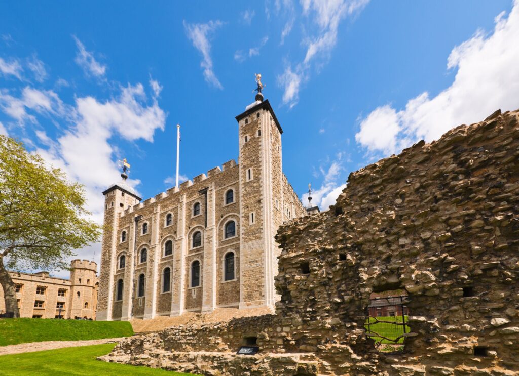 An old light bright building of the Tower of London against a bright blue sky.