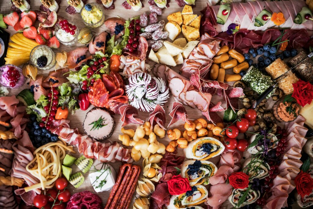 A full Smörgåsbord iwth meat, vegetables, fruit and cheese.